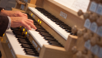 Mannen handen die orgel bespeelt met 3 lagen toetsen en registers