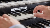 Handen die de witte toetsen van een donker Johannus orgel raken