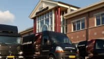 Zwarte busjes en vrachtwagen voor het pand van johannus